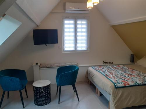 - une chambre avec un lit et deux chaises bleues dans l'établissement Le plan d'eau, à Civray-de-Touraine