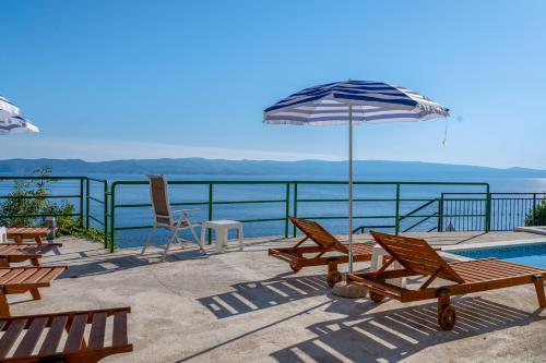 a patio with chairs and an umbrella and a pool at Apartments with pool Maraska in Brela
