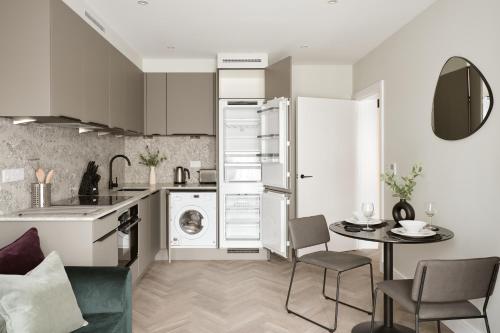 a kitchen and dining room with a washer and dryer at London City East by Viridian Apartments in London