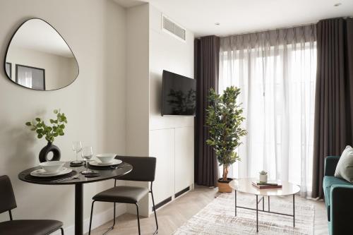 a living room with a table and a mirror at London City East by Viridian Apartments in London