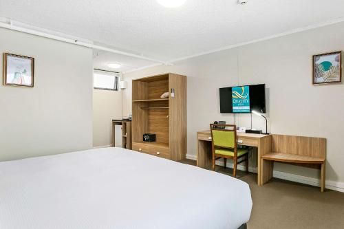a bedroom with a bed and a desk with a computer at Quality Inn Sunshine Haberfield in Sydney