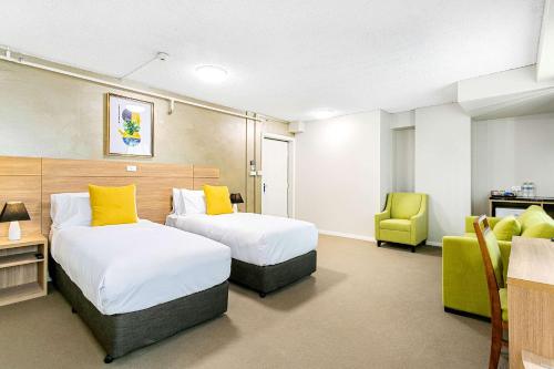 a hotel room with two beds and a chair at Quality Inn Sunshine Haberfield in Sydney
