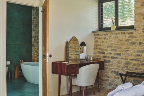 a bathroom with a tub and a desk and a sink at The Cowshed in Glastonbury