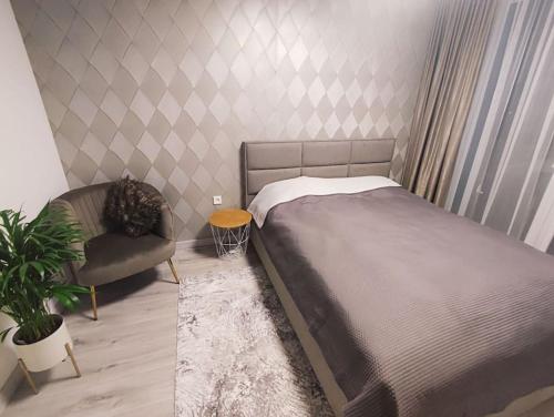 een slaapkamer met een bed en een stoel en een plant bij Kaunas Castle Apartment in Kaunas