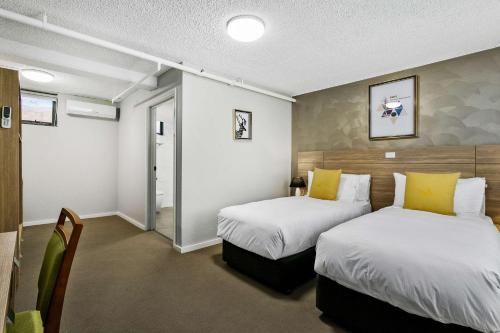 a hotel room with two beds and a hallway at Quality Inn Sunshine Haberfield in Sydney