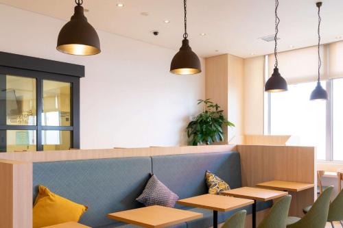 a restaurant with tables and chairs and pendant lights at Comfort Hotel Kochi in Kochi