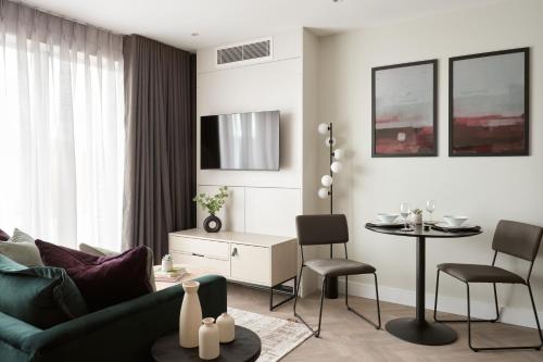 a living room with a green couch and a table at London City East by Viridian Apartments in London