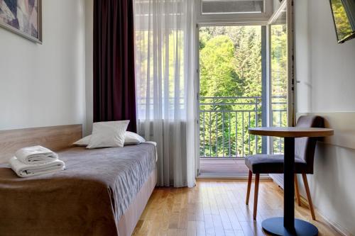 a bedroom with a bed and a window with a balcony at Silesia Krynica in Krynica Zdrój