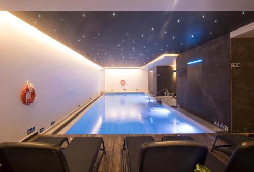 a large swimming pool in a building with chairs at Solana Hotel & Spa in Mellieħa
