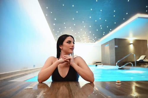 a woman sitting on the floor next to a swimming pool at Solana Hotel & Spa in Mellieħa