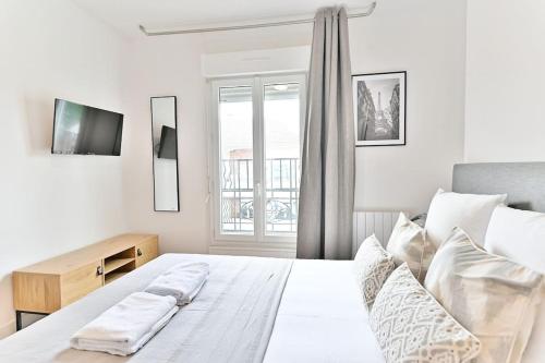 une chambre blanche avec un lit et une fenêtre dans l'établissement Studio Sympathique proche de Paris - Montreuil, à Montreuil