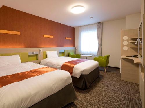 a hotel room with two beds and a television at Comfort Hotel Miyazaki in Miyazaki