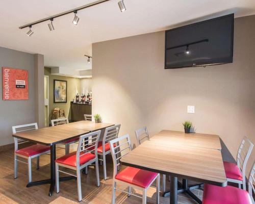 a dining room with two tables and chairs and a flat screen tv at Comfort Inn Airport East in Quebec City