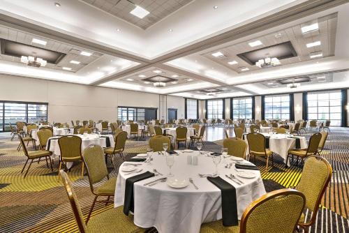 a large room with tables and chairs in a room with windows at Hotel Le Victorin, an Ascend Hotel Collection Member in Victoriaville