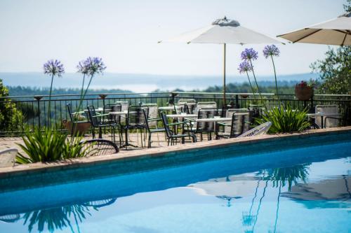 a swimming pool with tables and chairs and an umbrella at Villa Clodia Relais in Manziana