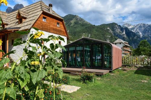 a house with a greenhouse on the side of it at Guesthouse Prrockaj Theth in Theth