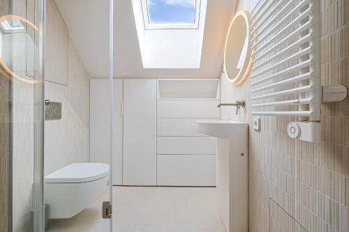 a bathroom with a toilet and a skylight at Laikas Prie Marių Apartments Waterfront, by Cohost in Preila