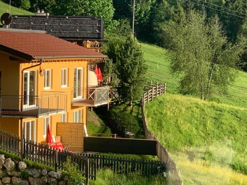a yellow house on a hill with a fence at Almlodge Flachau in Flachau