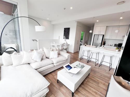 a living room with a white couch and a table at Luxury 2 Bedroom Apartment with cocktail bar and espresso machine in Auckland