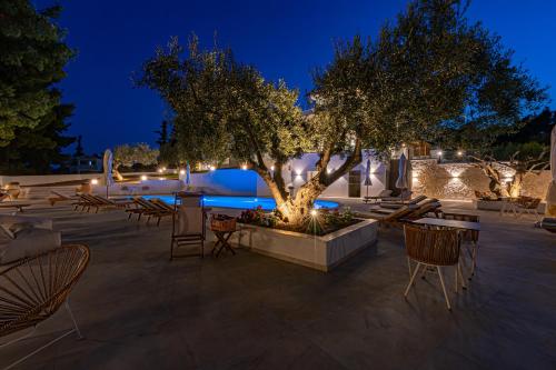 a patio with a tree and chairs at night at Serenity Hill in Paliouri