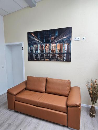 a brown couch in a room with a picture on the wall at Old Factory Living in Adelsdorf