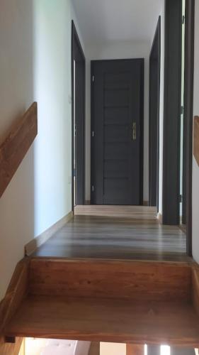 an empty hallway with a wooden floor and a black door at Wellness Chata na Vysočině in Bohdalov