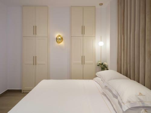 a bedroom with a white bed and white cabinets at Golden Luxury Suites in Balíon