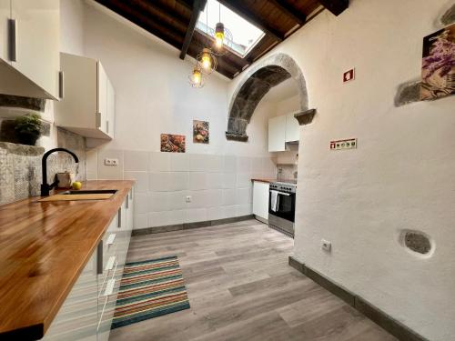 a kitchen with white walls and a wooden counter top at AZ Solar Cottage and Secret Garden in São Vicente Ferreira