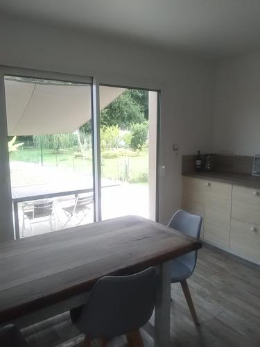 une table à manger avec deux chaises et une grande fenêtre dans l'établissement Maison neuve tout confort Soulac sur Mer, à Soulac-sur-Mer