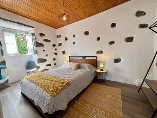 a bedroom with a bed with rocks on the wall at AZ Solar Cottage and Secret Garden in São Vicente Ferreira