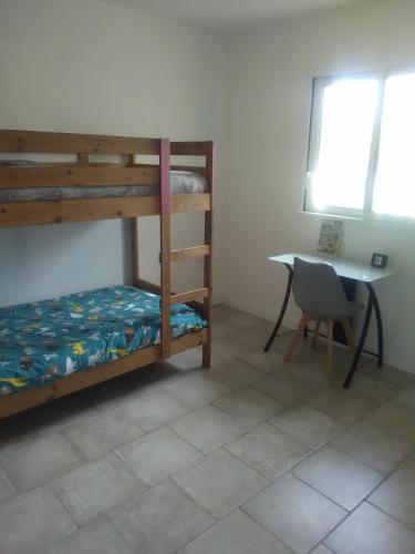 Cette chambre dispose de lits superposés, d'une table et d'un bureau. dans l'établissement Maison neuve tout confort Soulac sur Mer, à Soulac-sur-Mer