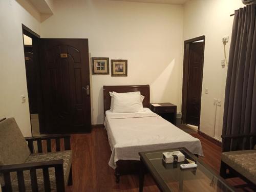 a bedroom with a bed and a chair and a table at Shelton Hotel Johar Town Lahore in Lahore