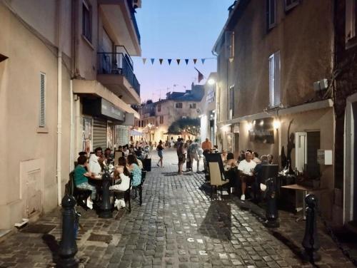 a group of people sitting at tables on a street at Appartement EMMA Quartier historique à 400m de la mer in Saint-Raphaël
