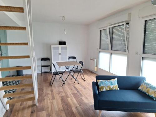 un salon avec un canapé bleu et une table dans l'établissement Appartement calme paisible, à Pérenchies