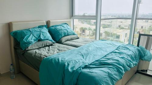 a bed with blue comforter in a room with a window at Damac Golf vita in Dubai