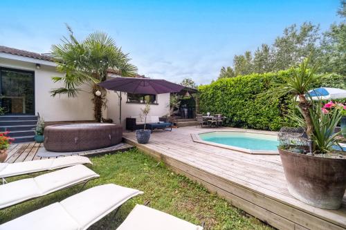 une cour arrière avec une piscine et une terrasse en bois dans l'établissement La Maison Riquet - Maison avec jacuzzi, à Labège