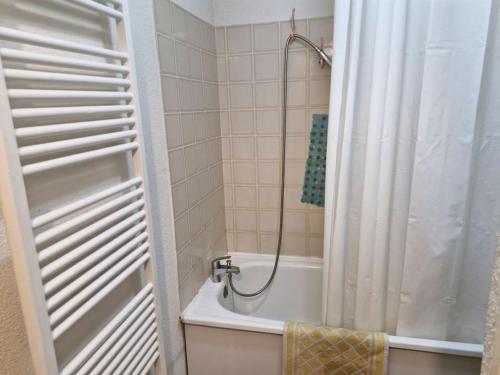 La salle de bains est pourvue d'une baignoire et d'une douche avec rideau de douche. dans l'établissement Appartement au pied des pistes, à La Joue du Loup