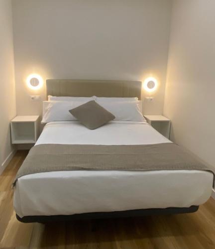 a bedroom with a large bed with two lamps at Apartamentos Buenos Aires,en el centro de Ribadeo con vistas a la ría in Ribadeo