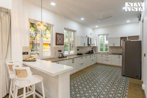 a large kitchen with white cabinets and a refrigerator at StayVista at Casa Armeh - Pool, BBQ in Siolim