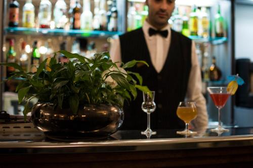 a man in a tuxedo standing at a bar with a plant at Royal Hotel in Cosenza