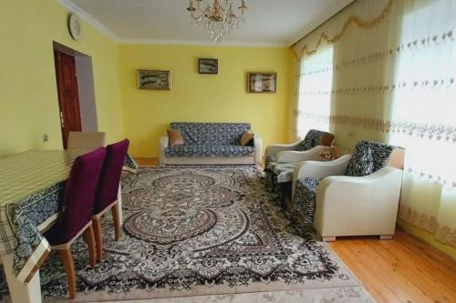 a living room with a table and chairs and a rug at Mammadaghali rental house in Mǝmmǝdağalı