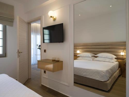 a bedroom with two beds and a television on a wall at Golden Luxury Suites in Balíon