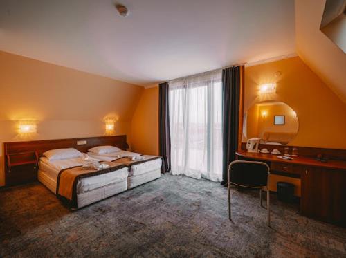 a bedroom with a bed and a desk and a window at Saint George Hotel & Medical Spa in Pomorie