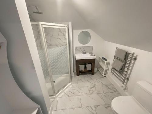 a white bathroom with a shower and a sink at The Boardwalk Inn in Summerside