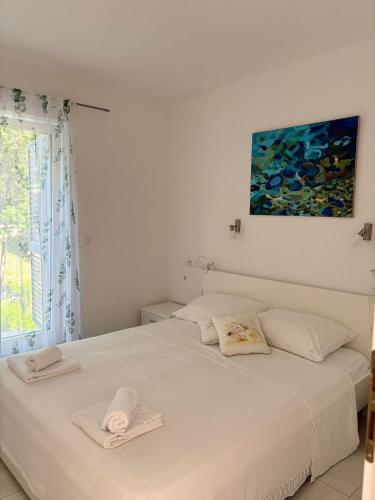 a white bedroom with a bed with two towels on it at Villa Matovica in Kampor