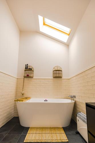 a large white tub in a bathroom with a skylight at IoanaGuestHouse in Turda