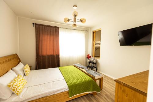 a bedroom with a bed with a green blanket at IoanaGuestHouse in Turda