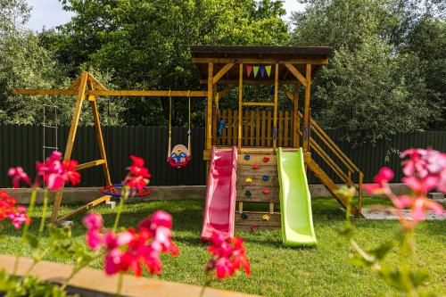 a playground in a yard with pink flowers at IoanaGuestHouse in Turda