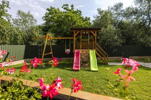 a playground in a yard with pink flowers at IoanaGuestHouse in Turda