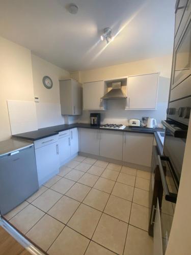 a kitchen with white cabinets and a tile floor at Lovely 3 bed house in Crosby in Crosby
